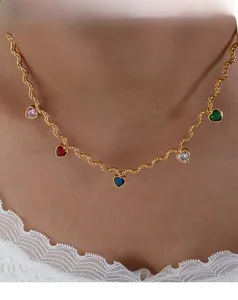 Close-up of golden rope chain necklace with five colorful heart-shaped gemstone pendants