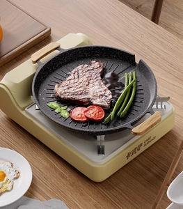 Top view of non-stick maifan stone grill pan with wood handles searing steak on a card furnace