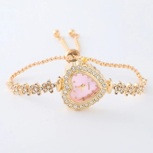 Macro detail of golden heart-shaped watch face with pink dial and floral rhinestone strap