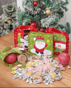Detail of Christmas felt gift bags with Santa and snowman embroidery on wood surface