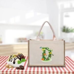 Detailed view of canvas tote bag with floral letter D print on a picnic tablecloth