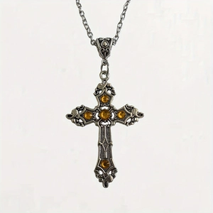Macro detail of gothic silver cross necklace with vintage engravings and amber stones