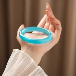 Detail of sky blue cat eye stone bangle showing smooth texture on model hand