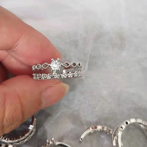 Close-up of stacked silver lace rings with rhombic hollow design and zircon inlay