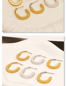Detailed view of U-shaped gold and silver stainless steel earrings on a ceramic tray