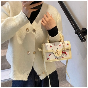 Detail of cream crossbody bag with cherry print and golden petal swivel lock clasp