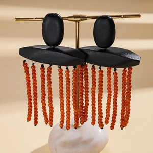 Detail of bohemian wood earrings with black geometric shapes and orange bead tassels