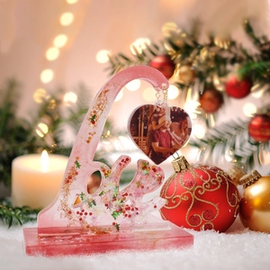 Macro shot of DIY pink resin LOVE photo frame and heart pendant in festive scene
