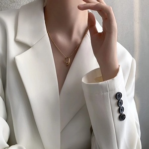 Minimalist gold irregular geometric fluid pendant necklace worn with a white blazer