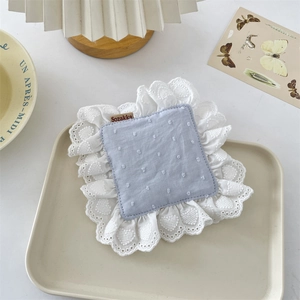 Detail of blue polka dot coaster with delicate white lace border and vintage brand tag