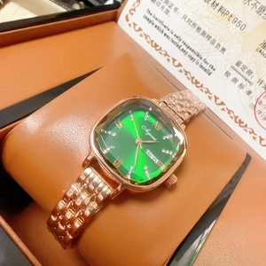 Detail of green sunray dial with Roman numerals and day-date display on gold watch