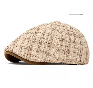 Detail view of beige tweed newsboy cap with contrasting suede brim and woven texture