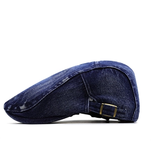 Detail of dark blue washed denim flat cap featuring adjustable brass side buckle