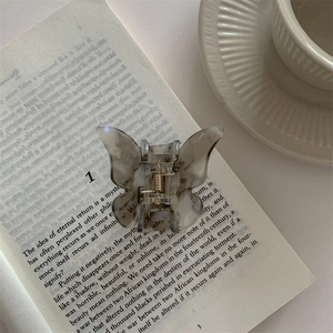 Detail of marble pattern butterfly hair claw clip placed on a book with soft natural light