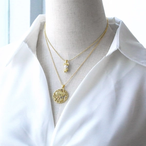 Detail of a layered gold necklace featuring a boy girl pendant and colorful zircon ring