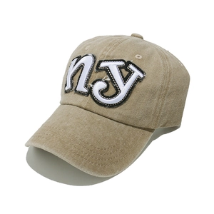 Detail of khaki NY embroidery on vintage washed cotton baseball cap with curved brim