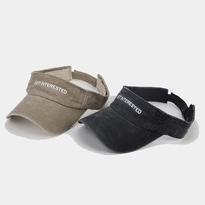 Detail of washed cotton sun visors with embroidered 'NOT INTERESTED' text on front