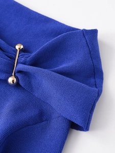 Close-up of dark blue ribbed knit fabric with decorative gold metal bar hardware