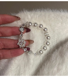 Close-up of pearl bracelet featuring zircon snowflake charms and silver star pendants