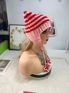 Close-up of pink and red striped knit hat featuring cute cat ears and floral ties