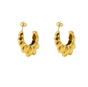 Close-up of golden croissant-style twisted hoop earrings with polished steel finish