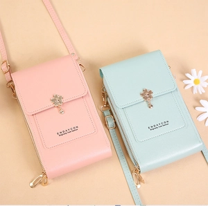 Detail of pink and light blue crossbody phone bags with floral buckles and PU texture