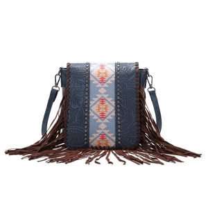 Detail of bohemian cross-body bag with floral embossing, geometric fabric and long fringes