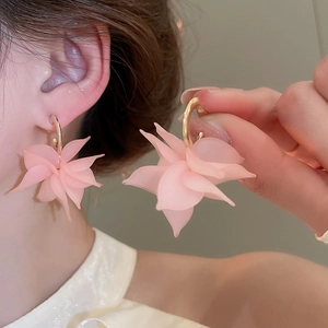 Detail of pink acrylic petal C-shape earrings showing translucent matte texture and gold studs