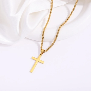 Polished gold stainless steel cross pendant on thick rope chain over white silk background