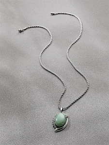 Detail of silver twist chain necklace with green oval gemstone and micro-inlaid diamonds