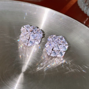 Dettaglio macro di orecchini a cubo in argento con brillanti zirconi su superficie metallica