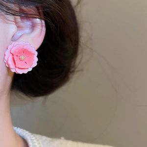 Gros plan de boucles d'oreilles fleurs en résine rose avec cœur doré pour un style élégant
