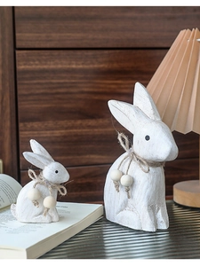 Detail van twee witte vintage houten konijnen met touw en kralen voor de tuin decoratie