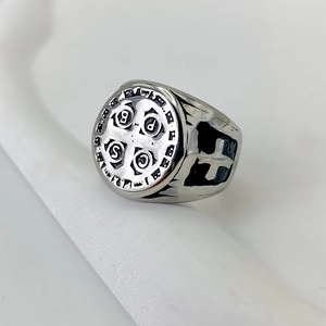 Gros plan sur une bague rétro en acier avec motif de croix et médaille Saint-Benoît