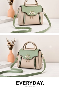 Detail of color-block handbag showing golden swan clasp and metallic ring handle