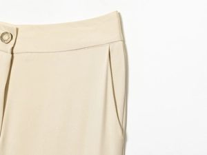 Détail du pantalon à taille haute et jambe large en sergé avec bouton doré élégant