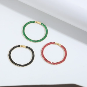 Minimalist gold bracelets set with emerald, onyx, and ruby square zircons on white backdrop