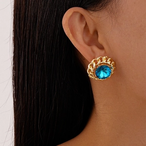 Close-up of a vintage chain earrings with a blue gemstone centerpiece on a model's ear