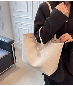 Detailed macro view showing the soft lychee grain texture of the beige leather tote bag