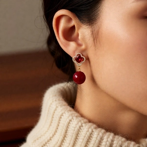 Detail of vintage ruby red pearl earrings with gold floral studs worn on a model