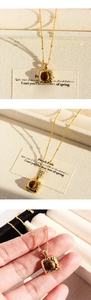 Detailed view of a vintage square pendant with a tiger eye stone on a gold beaded chain