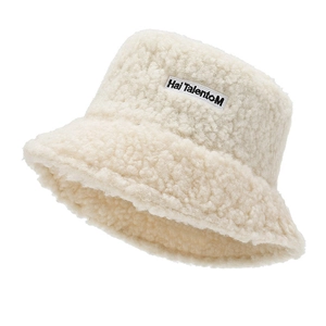 Detail of soft beige faux lamb wool bucket hat featuring a black lettered woven label