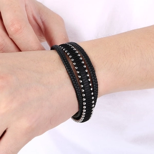 Detail of multi-layer braided black leather bracelet with silver metal beads on wrist