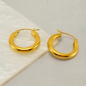 Classic gold hoop earrings in chunky design on white marble and grey fabric background