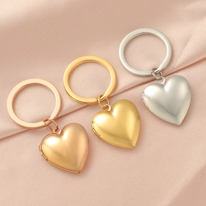 Three heart-shaped photo locket keychains in gold and rose gold on pink silk fabric