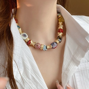 Detailed view of handmade colorful ceramic beads and gold twisted metal spacers on necklace