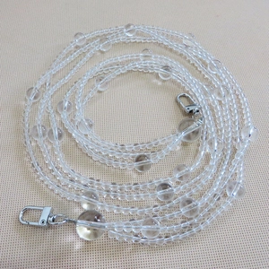 Macro detail of transparent beaded bag chain with silver metal lobster clasps on each end