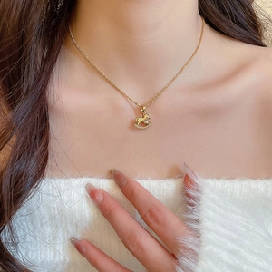 Detailed close-up of a gold-plated rocking horse pendant on a delicate link chain necklace
