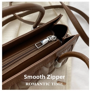 Detailed macro of smooth silver metal zipper on premium quilted dark brown leather bag