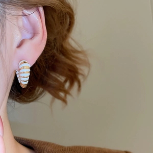 Gros plan de boucles d'oreilles cœur émaillées dorées et blanches sur un mannequin